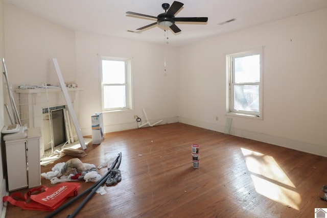 living room with a tiled fireplace, ceiling fan, hardwood / wood-style flooring, and a healthy amount of sunlight