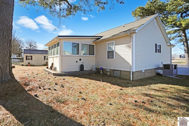 back of house featuring central AC, a storage shed, and a lawn