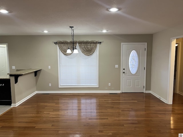 foyer entrance with dark wood-type flooring and a notable chandelier