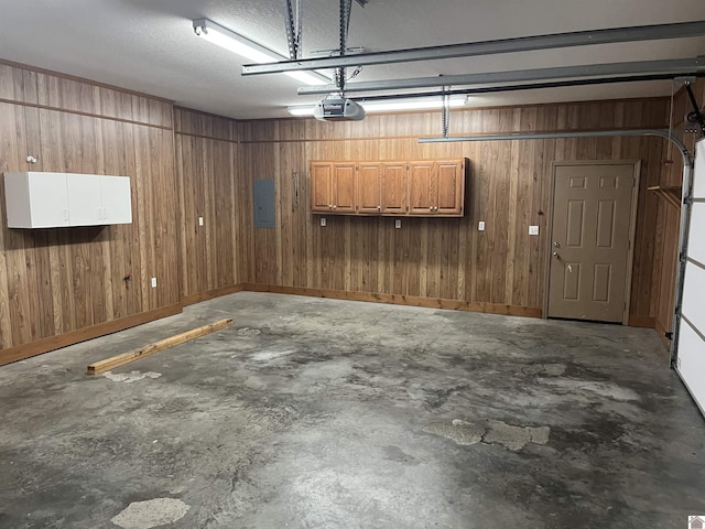 garage with a garage door opener, wooden walls, and electric panel