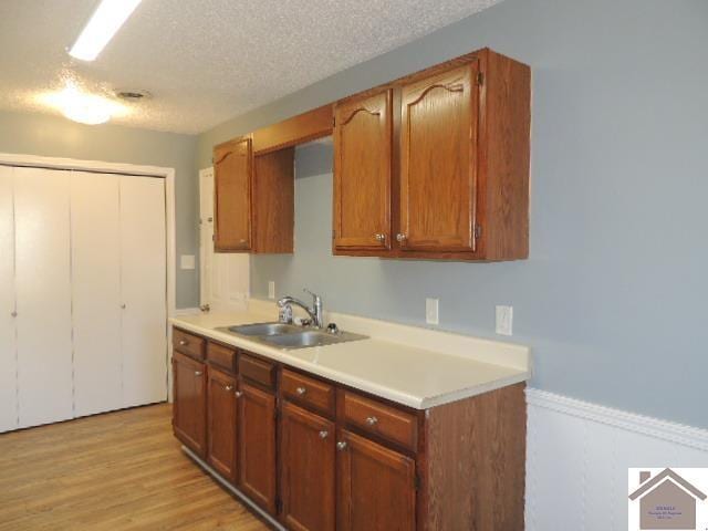 kitchen with light hardwood / wood-style floors, sink, and a textured ceiling