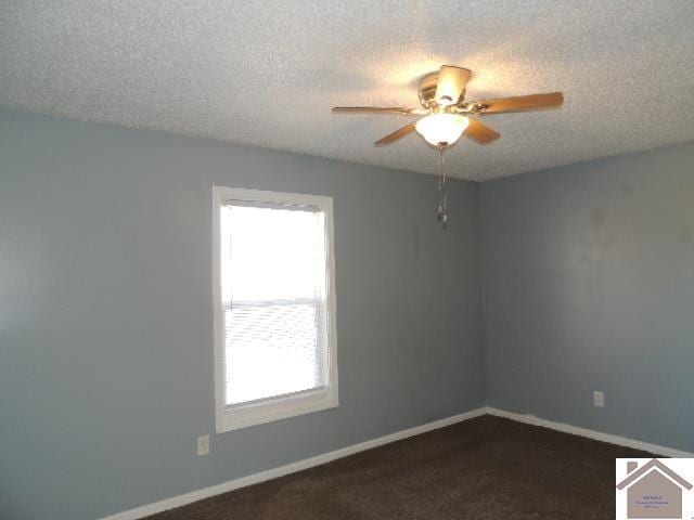 empty room with ceiling fan, a healthy amount of sunlight, a textured ceiling, and dark carpet