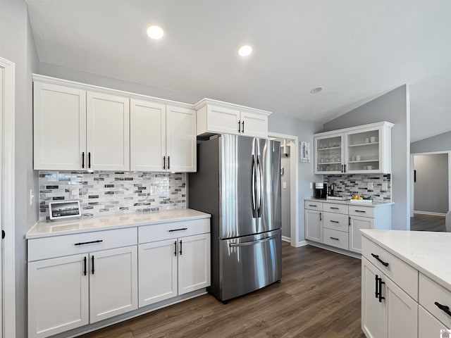 kitchen with stainless steel refrigerator, lofted ceiling, dark wood-type flooring, and white cabinets