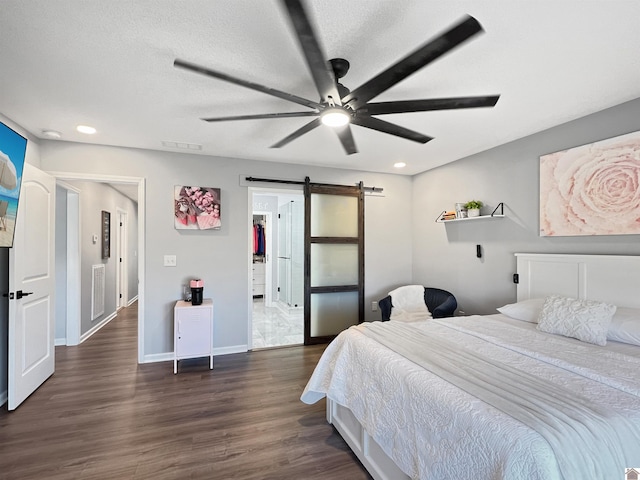 bedroom with ceiling fan, a barn door, and dark hardwood / wood-style flooring