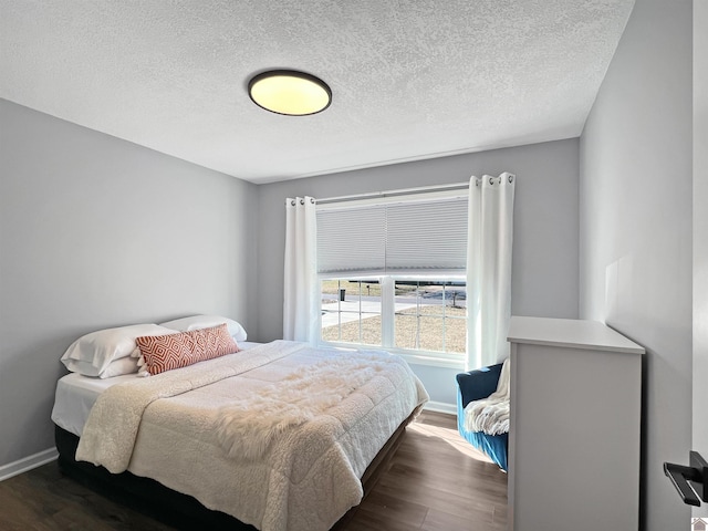 bedroom with dark hardwood / wood-style floors and a textured ceiling