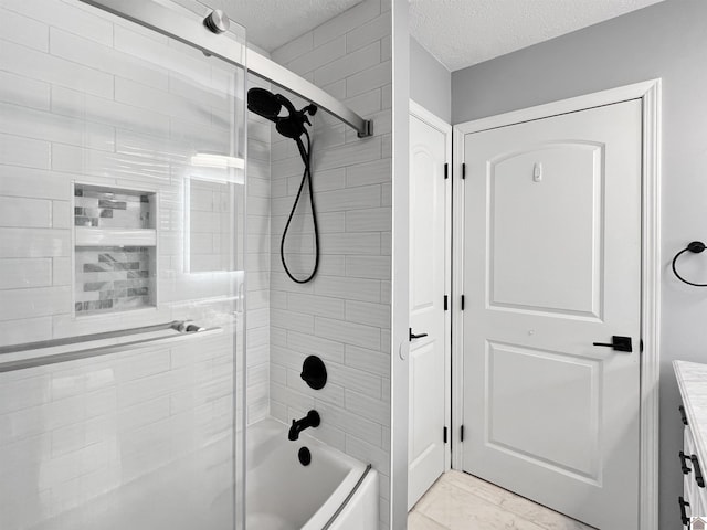 bathroom with vanity, a textured ceiling, and tiled shower / bath