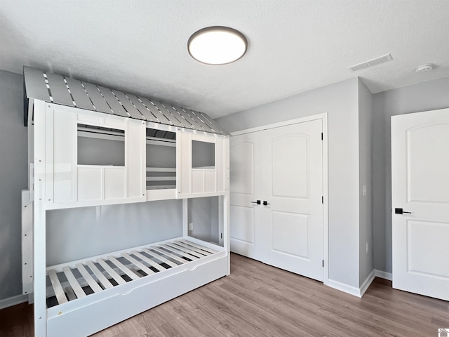 unfurnished bedroom with hardwood / wood-style flooring, a textured ceiling, and a closet