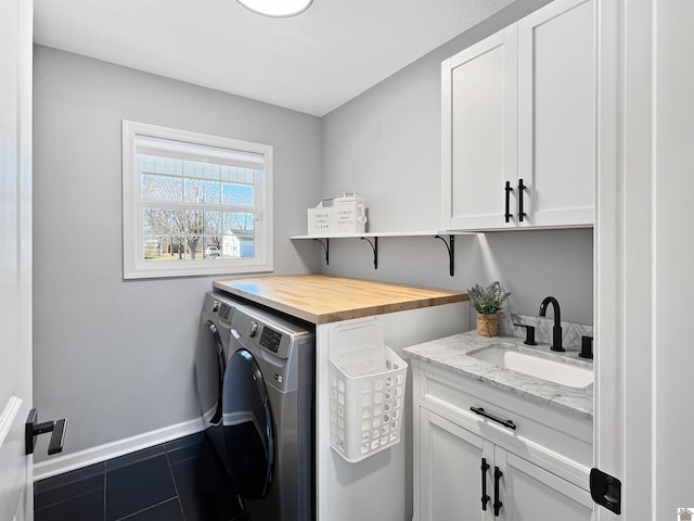 clothes washing area with sink, cabinets, washing machine and clothes dryer, and dark tile patterned flooring