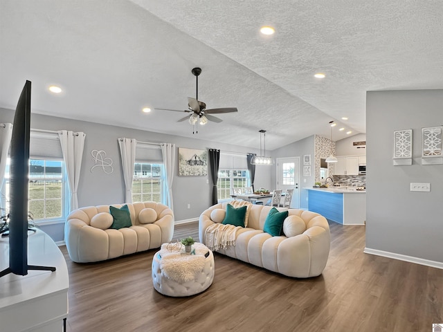 living room with ceiling fan, dark hardwood / wood-style floors, vaulted ceiling, and a textured ceiling