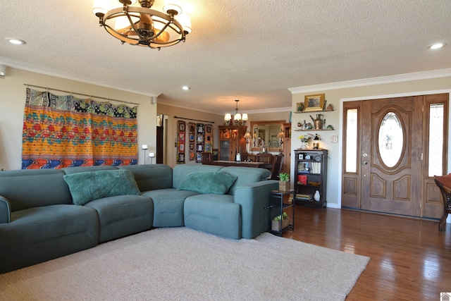 living room featuring an inviting chandelier, ornamental molding, dark wood-type flooring, and a textured ceiling