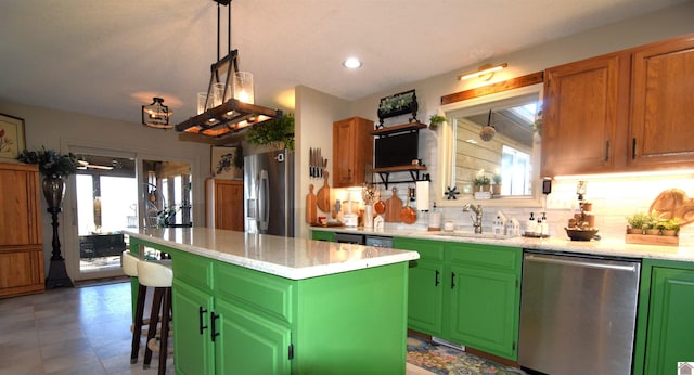 kitchen with appliances with stainless steel finishes, a center island, a breakfast bar, and green cabinetry