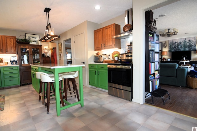 kitchen featuring pendant lighting, wall chimney range hood, a breakfast bar, electric range, and a kitchen island