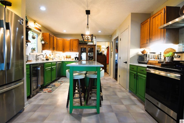 kitchen with wine cooler, a kitchen island, pendant lighting, stainless steel appliances, and wall chimney range hood