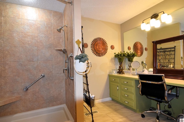 bathroom featuring a tile shower, vanity, and a textured ceiling