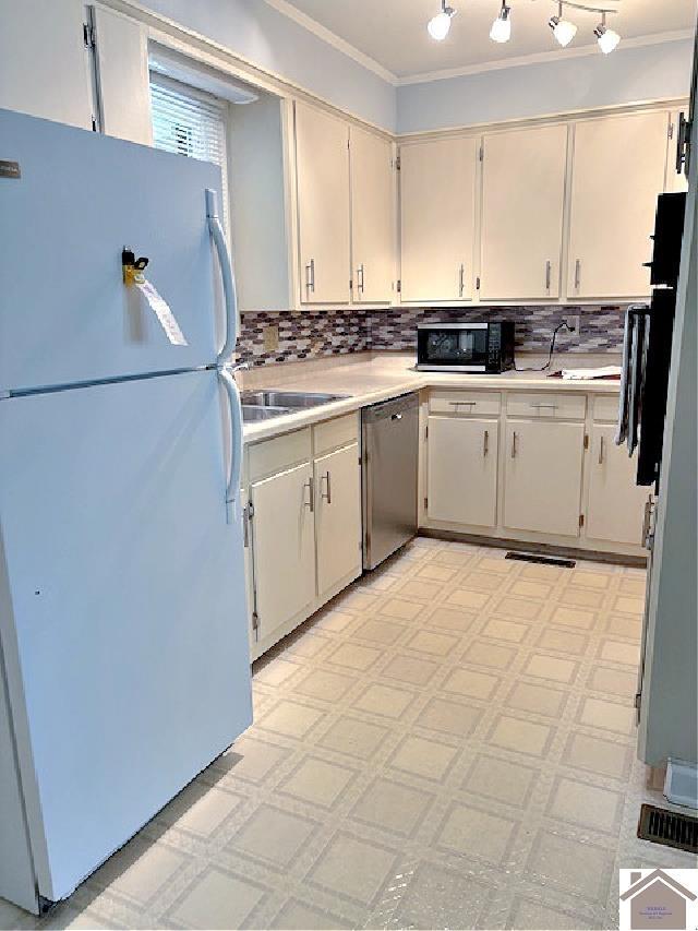 kitchen featuring tasteful backsplash, crown molding, stainless steel dishwasher, and white refrigerator