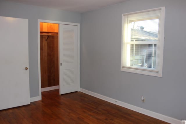 unfurnished bedroom with dark hardwood / wood-style floors and a closet