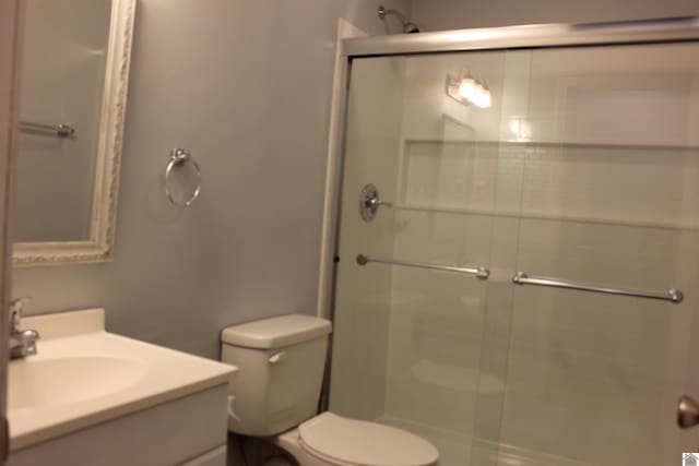 bathroom with vanity, a shower with shower door, and toilet