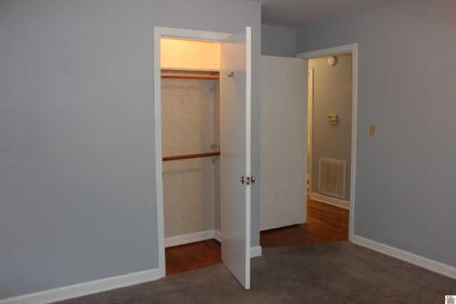 unfurnished bedroom featuring dark carpet and a closet