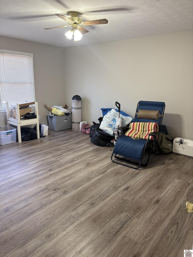 miscellaneous room featuring ceiling fan, wood-type flooring, and a textured ceiling