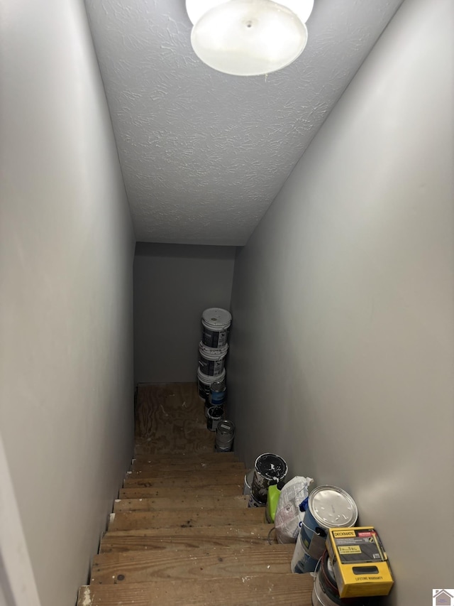 stairway with hardwood / wood-style floors and a textured ceiling