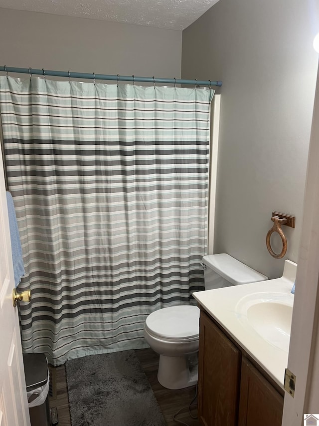 bathroom with vanity, wood-type flooring, a textured ceiling, and toilet