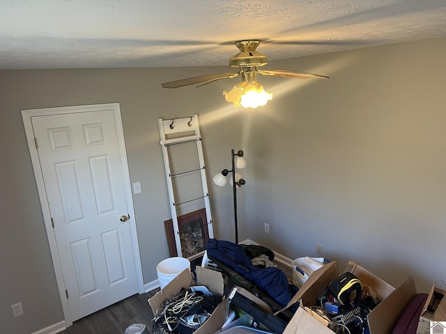 miscellaneous room featuring dark wood-type flooring, ceiling fan, and a textured ceiling