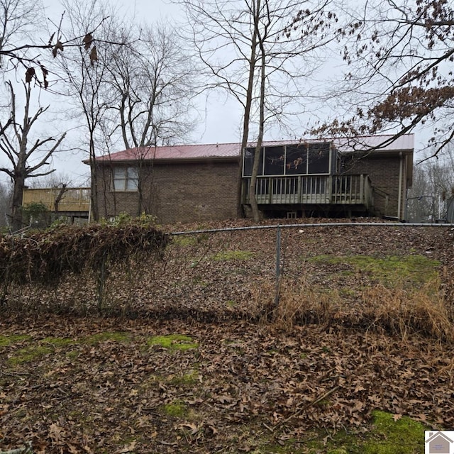 rear view of house featuring a sunroom and a deck