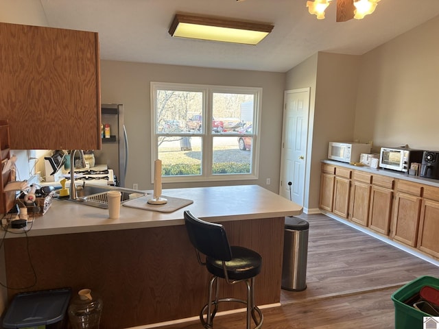 kitchen featuring stainless steel refrigerator, a kitchen breakfast bar, kitchen peninsula, and hardwood / wood-style floors