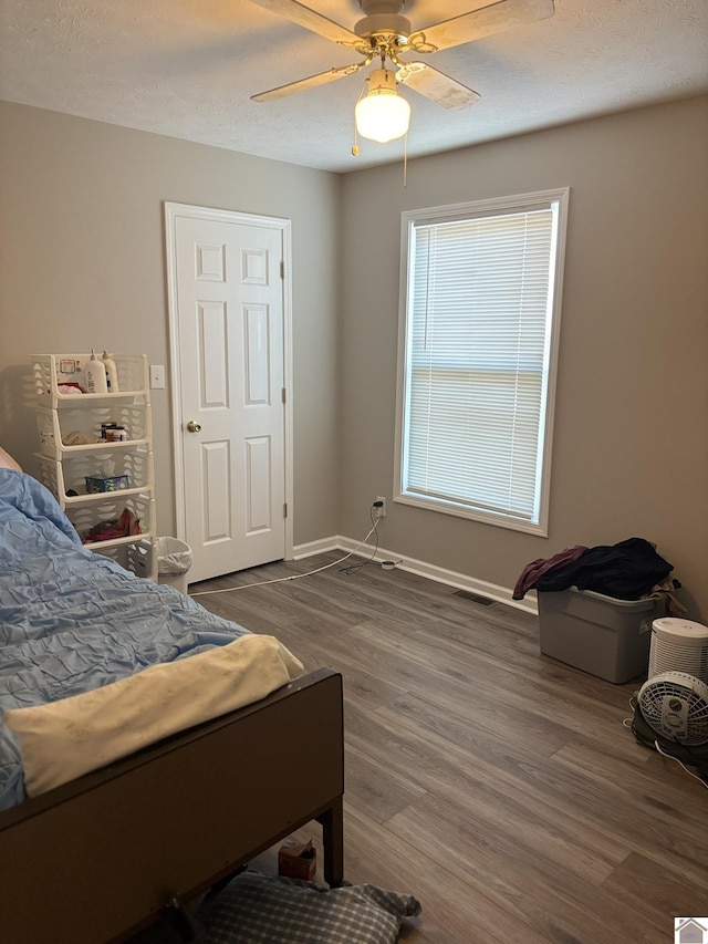 bedroom with ceiling fan, dark wood-type flooring, and a textured ceiling