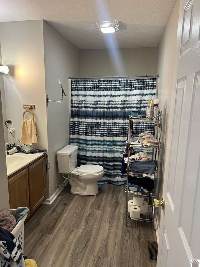 bathroom featuring toilet, a textured ceiling, vanity, curtained shower, and hardwood / wood-style flooring