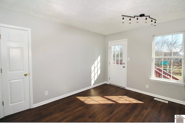 interior space featuring dark wood-type flooring, a healthy amount of sunlight, rail lighting, and a textured ceiling