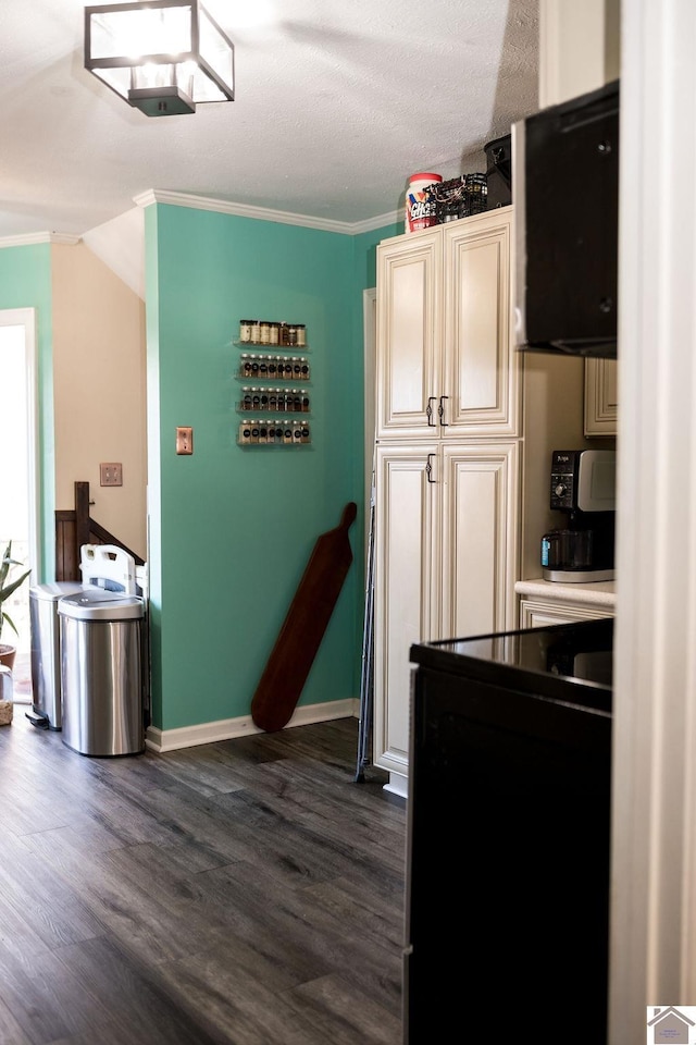 kitchen with baseboards, dark wood finished floors, ornamental molding, light countertops, and cream cabinetry