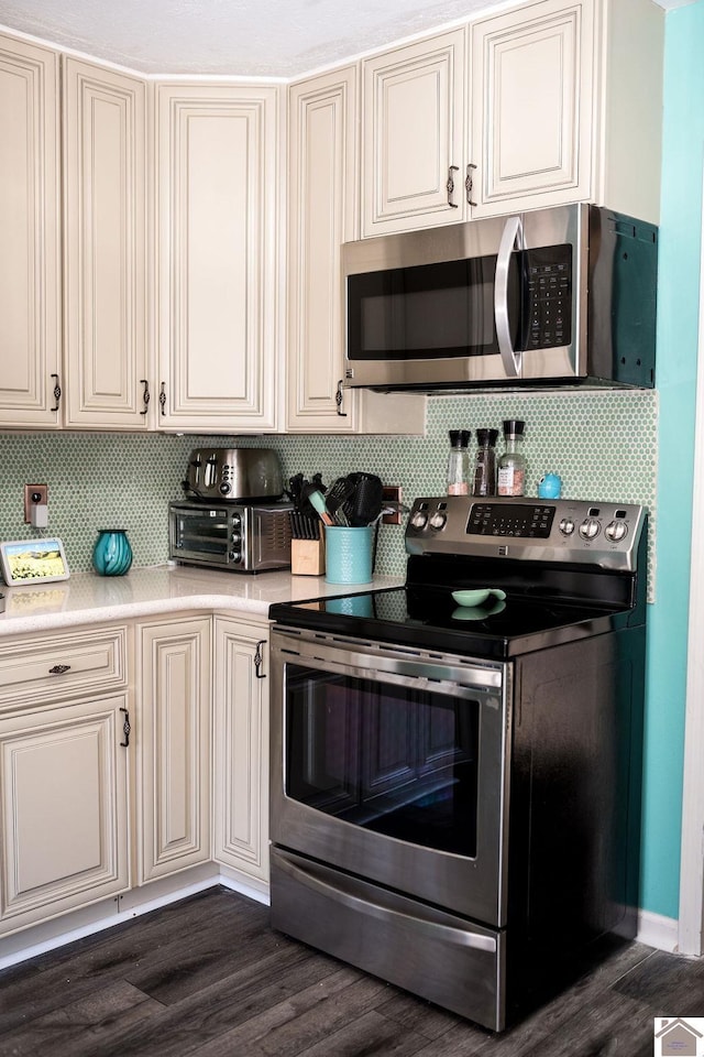 kitchen with dark wood-type flooring, tasteful backsplash, stainless steel appliances, and light countertops