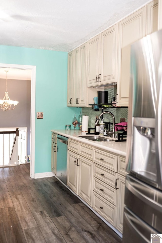 kitchen featuring dark wood-style floors, appliances with stainless steel finishes, an inviting chandelier, light countertops, and a sink