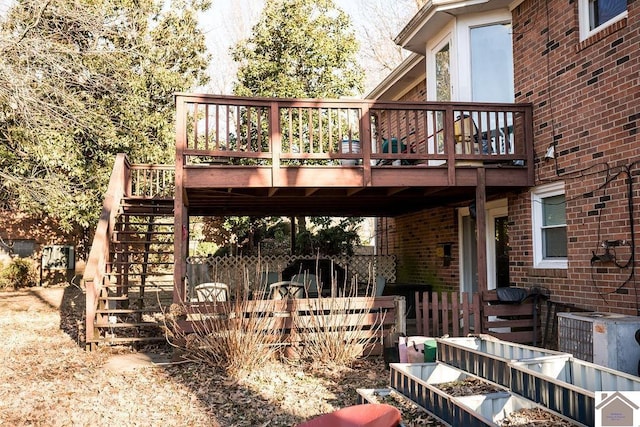 exterior space with a wooden deck, stairs, cooling unit, and brick siding