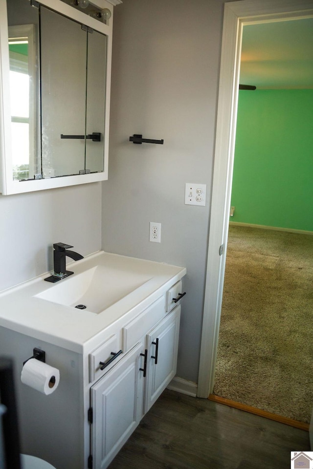 bathroom with wood finished floors, vanity, and baseboards