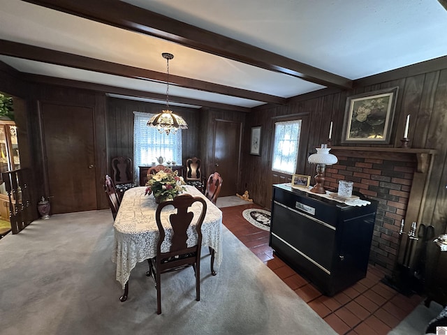 dining area featuring beamed ceiling, a chandelier, and wood walls