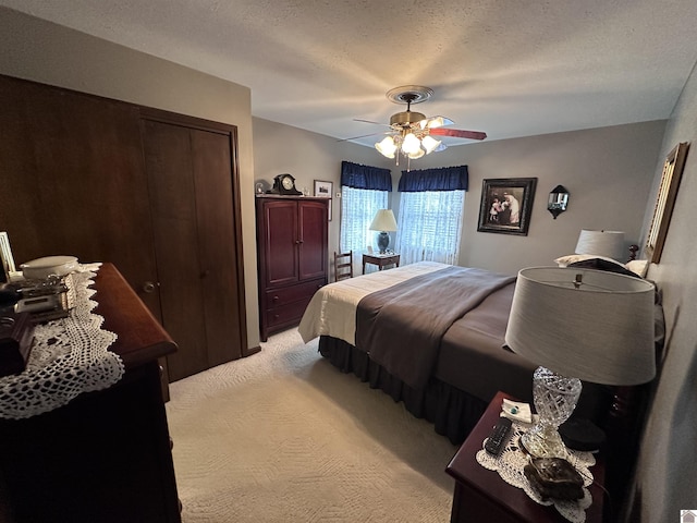 carpeted bedroom featuring ceiling fan, a closet, and a textured ceiling