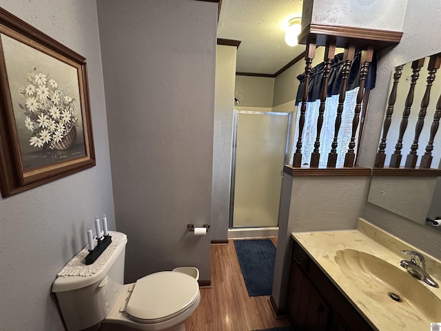 bathroom featuring a shower with shower door, hardwood / wood-style flooring, ornamental molding, vanity, and a textured ceiling