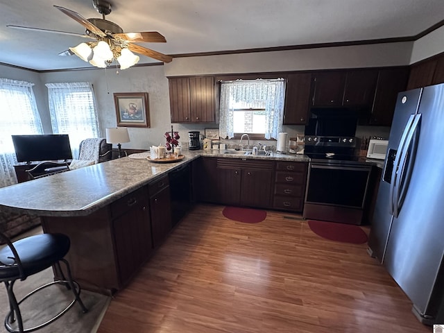 kitchen featuring dark brown cabinetry, sink, appliances with stainless steel finishes, kitchen peninsula, and hardwood / wood-style floors