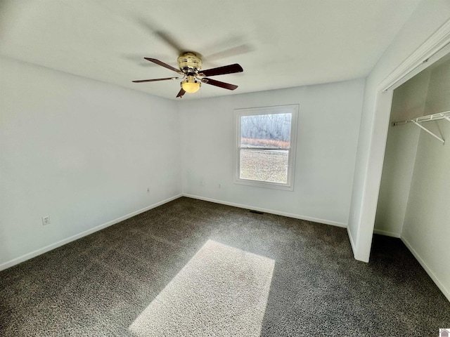 unfurnished bedroom featuring dark colored carpet, ceiling fan, and a closet