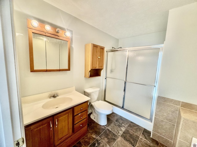 bathroom with vanity, a textured ceiling, a shower with shower door, and toilet