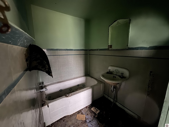 bathroom featuring sink, a bath, and tile walls