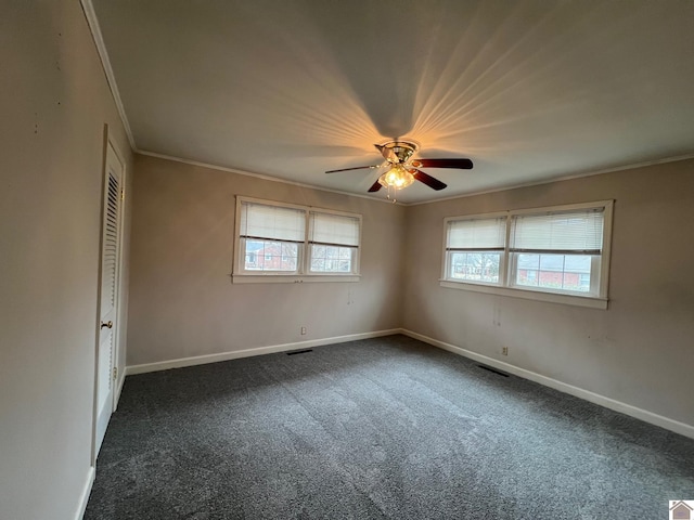 unfurnished room with ornamental molding, a wealth of natural light, ceiling fan, and dark carpet