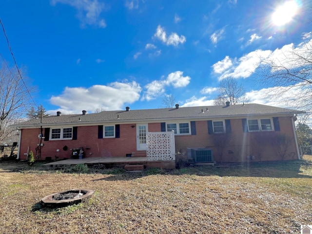 rear view of property with a yard, an outdoor fire pit, central AC, and a patio area