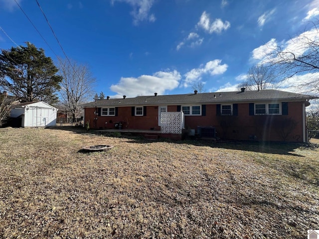 back of property featuring a storage unit, central AC unit, and a lawn