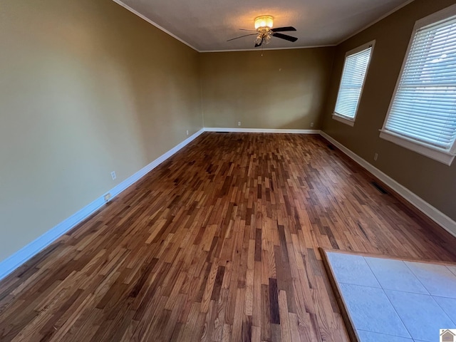 empty room featuring hardwood / wood-style flooring, ornamental molding, and ceiling fan