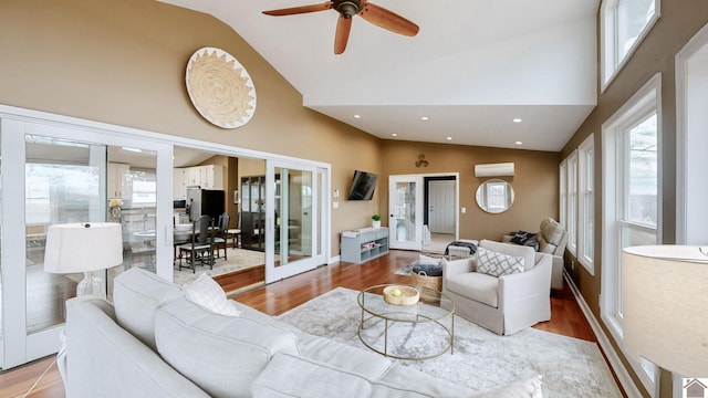 living room with a wall mounted air conditioner, a wealth of natural light, french doors, and light wood-type flooring