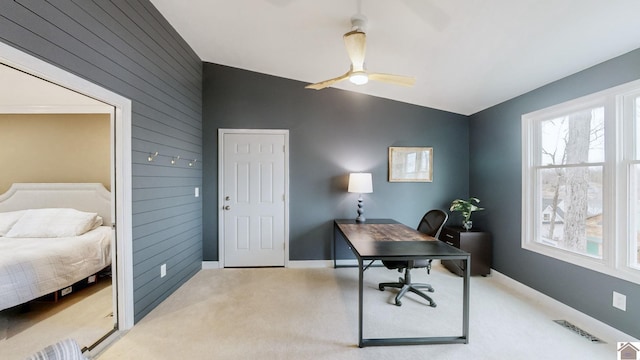 carpeted office with vaulted ceiling, wooden walls, and ceiling fan