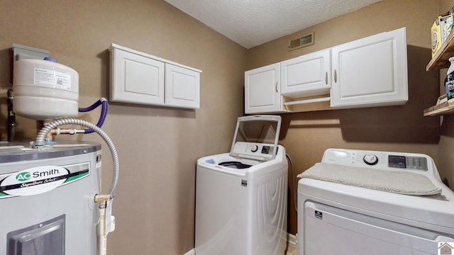 washroom featuring separate washer and dryer, cabinets, water heater, and a textured ceiling